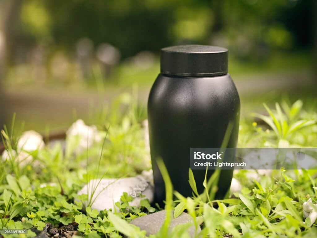 Black urn prepared for funeral at a green field